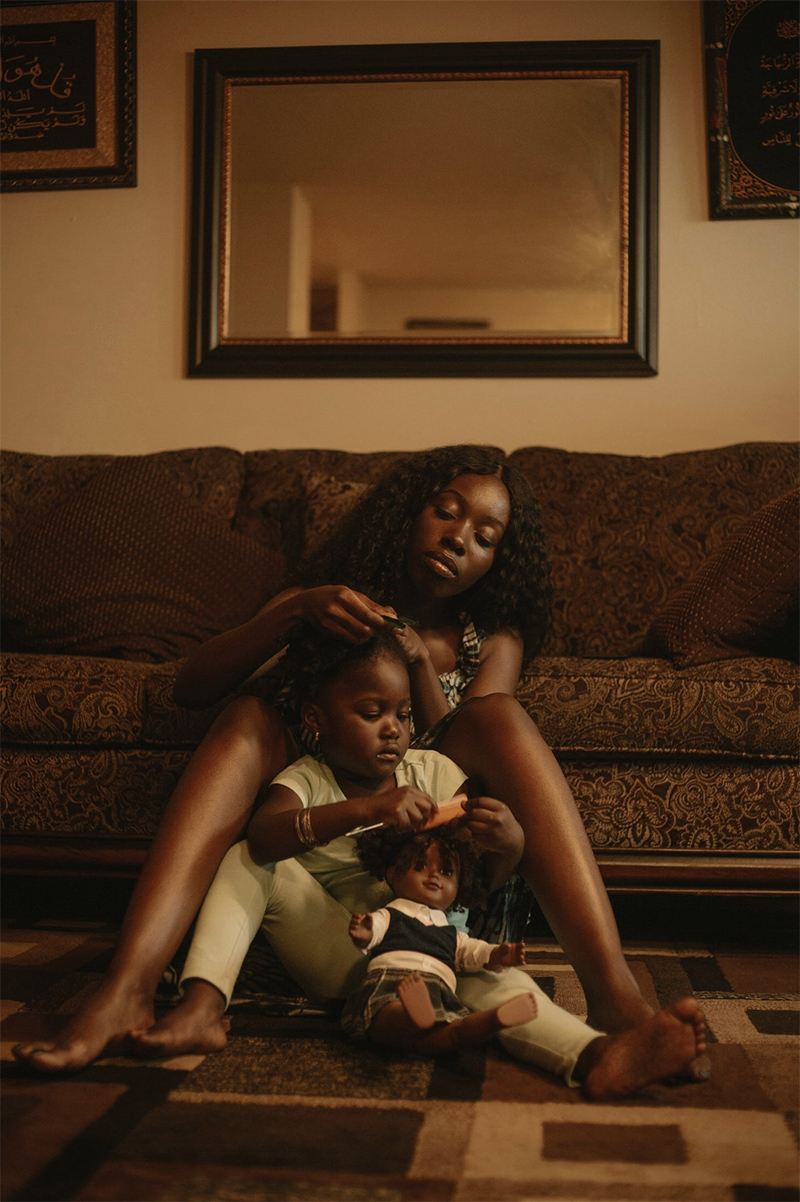 Una madre afrodescendiente peina el cabello a su hija.